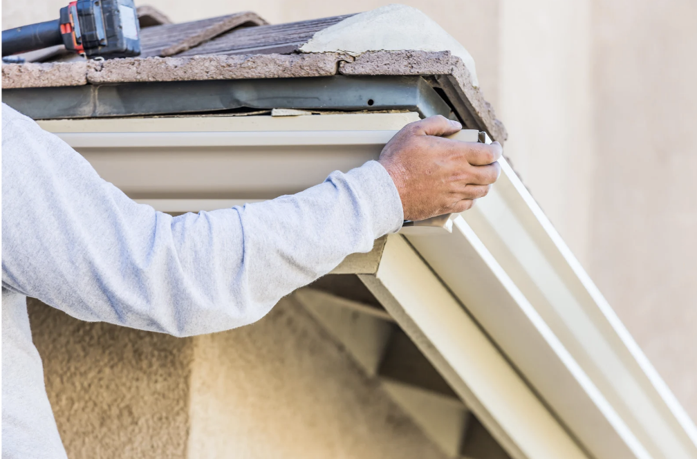 Indianapolis IN gutter repair contractor hand-fitting a replacement rain gutter section to a residential roofline